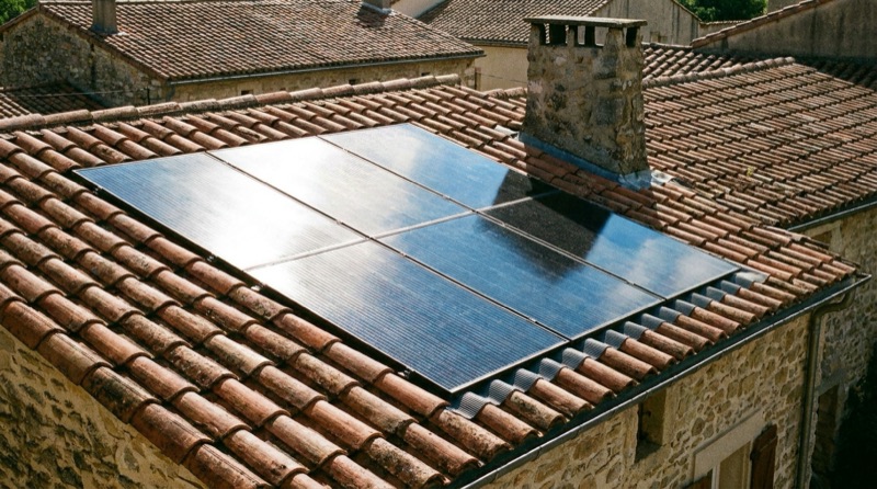 Panneaux photovoltaïques monocristallins posés sur un toit en tuiles d'une maison de village
